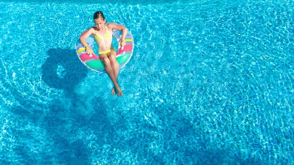 Widok z lotu ptaka z dziewczyna w basenie z góry, dziecko pływać na nadmuchiwanym pierścieniem pączek i ma zabawy w wodzie na rodzinne wakacje — Zdjęcie stockowe