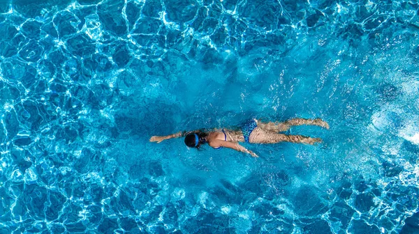Luftaufnahme einer Frau im Schwimmbadwasser von oben, tropisches Urlaubskonzept — Stockfoto