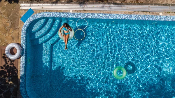 Vue aérienne de la belle fille dans la piscine d'en haut, nager sur beignet anneau gonflable et s'amuse dans l'eau pendant les vacances en famille — Photo