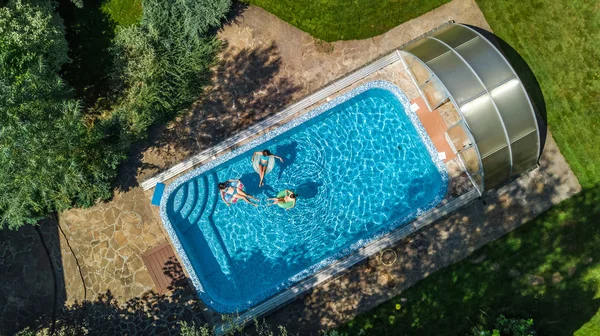 Vue aérienne du dessus de la famille dans la piscine d'en haut, la mère et les enfants nagent et s'amusent dans l'eau en vacances en famille dans la station hôtelière — Photo