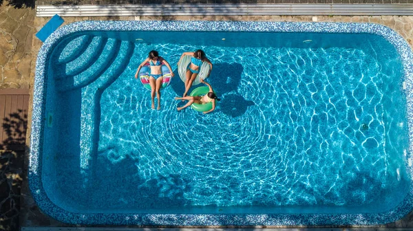 Vue aérienne du dessus de la famille dans la piscine d'en haut, la mère et les enfants nagent et s'amusent dans l'eau en vacances en famille dans la station hôtelière — Photo