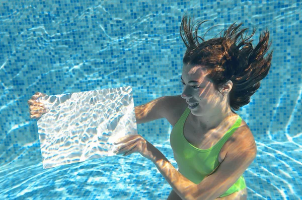 Mooi jong meisje holding wit blanco boord in zwembad onder water, fitness en plezier op familie vakantie — Stockfoto