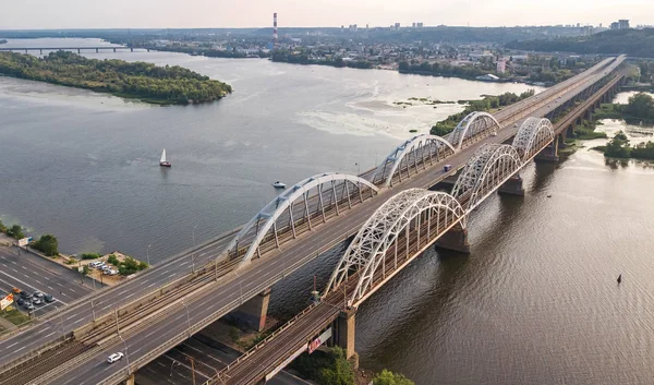 Otomobil ve demiryolu Darnitsky köprüden Dnieper Nehri yukarıdan, Kiev (Kiev) şehir günbatımı manzarası, Ukrayna Hava Üstten Görünüm
