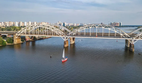 Top luchtfoto van Darnitsky brug, jachten en boten varen in Dnjepr above, de skyline van de stad van Kiev (Kyiv), Oekraïne — Stockfoto