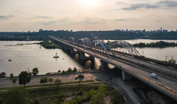 Otomobil ve demiryolu Darnitsky köprüden Dnieper Nehri yukarıdan, Kiev (Kiev) şehir günbatımı manzarası, Ukrayna Hava Üstten Görünüm