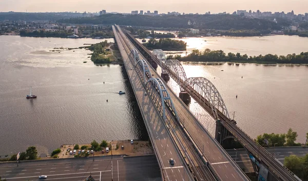 Otomobil ve demiryolu Darnitsky köprüden Dnieper Nehri yukarıdan, Kiev (Kiev) şehir günbatımı manzarası, Ukrayna Hava Üstten Görünüm — Stok fotoğraf