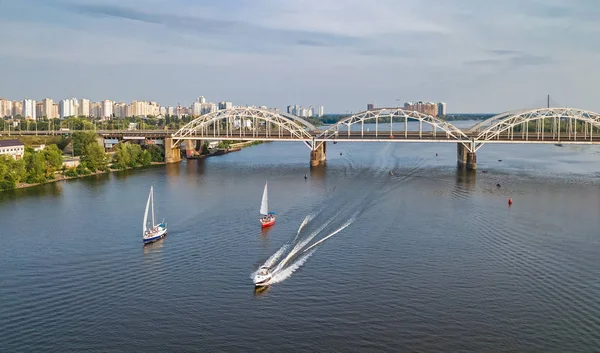 Vista aérea superior da ponte Darnitsky, iates e barcos navegando no rio Dnieper de cima, horizonte da cidade de Kiev (Kiev), Ucrânia — Fotografia de Stock