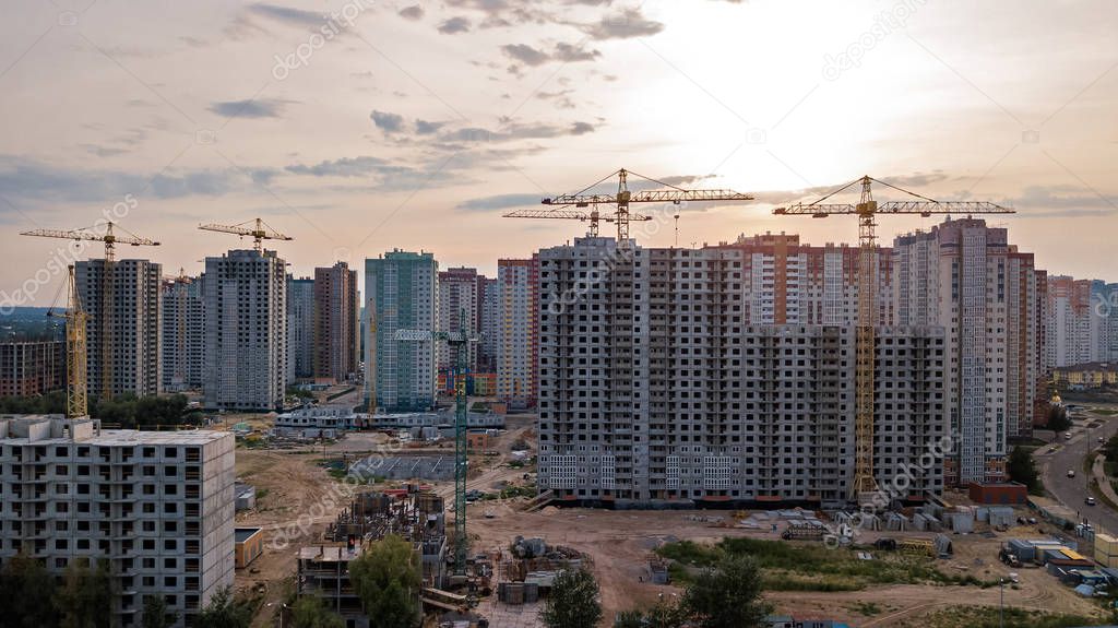 Aerial view of construction site of residential area buildings with cranes at sunset from above, urban skyline of Kyiv city, Ukraine