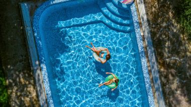 Hava üst yukarıdan, yüzme havuzunda çocukların mutlu çocuklar yüzmek şişme üzerinde çörek halka ve su ailecek tatile eğlenmek görüntülemek