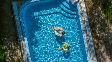 Hava üst yukarıdan, yüzme havuzunda çocukların mutlu çocuklar yüzmek şişme üzerinde çörek halka ve su ailecek tatile eğlenmek görüntülemek