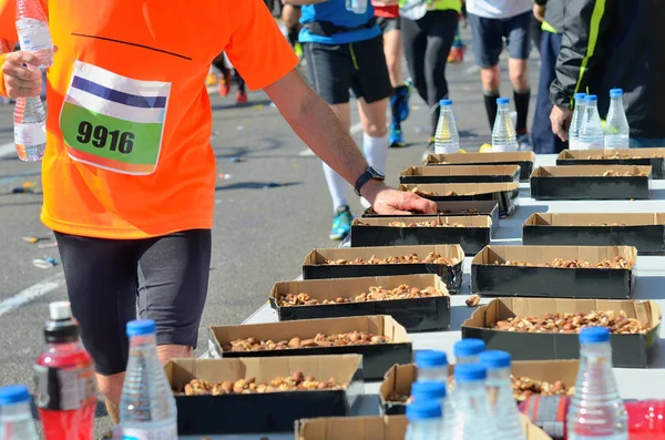 Maratona corrida de estrada, corredores mão tomando alimentos e bebidas no ponto de refresco, esporte, fitness e conceito de estilo de vida saudável — Fotografia de Stock