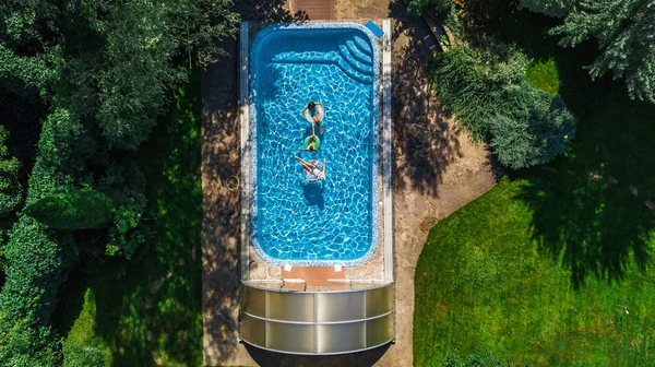 空撮トップ上からスイミング プール 子供たちの家族の膨脹可能なリング ドーナツに泳ぐ 家族での休暇に水の楽しさがあります — ストック写真