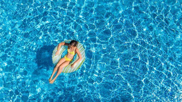 Havadan görünümü bir kız yukarıda, yüzme havuzunda Yüzme şişme halka çörek üzerinde çocuk ve eğlenir suda ailecek tatile