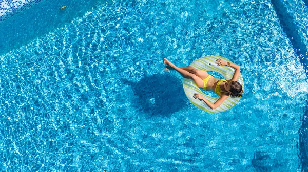 Havadan görünümü bir kız yukarıda, yüzme havuzunda Yüzme şişme halka çörek üzerinde çocuk ve eğlenir suda ailecek tatile