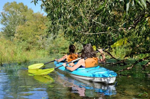 Family kayaking, mother and child paddling in kayak on river canoe tour having fun, active autumn weekend and vacation, fitness concept