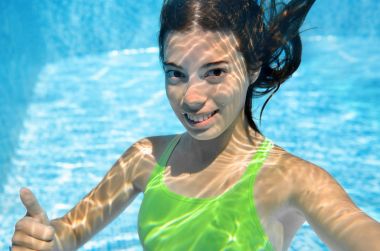 Girl swims in swimming pool underwater, happy active teenager dives and has fun under water, kid fitness and sport on family vacation on resort clipart