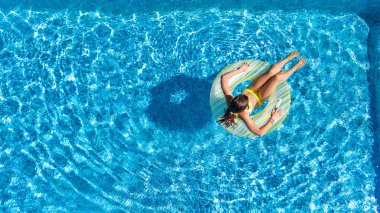 Yukarıdan, çocuk yüzer şişme halka çörek üzerinde yüzme havuzunda küçük kız hava en iyi görünümü, çocuk su eğlenceli aile tatil tatil vardır