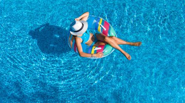 Yukarıdan, yüzme havuzunda güzel kızın hava üstten görünüm yüzmek şişme halka çörek üzerinde dinlenmek ve eğlenir suda ailecek tatile tropikal tatil