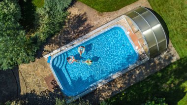 Hava üstten görünüm Yüzme Havuzu yukarıdan, mutlu anne ve çocuklar aile şişme halka çörek üzerinde yüzmek ve su aile tatil, tropikal tatil tatil eğlenmek