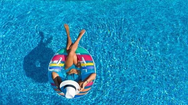 从上面的游泳池的美丽的女孩空中俯视 放松游泳的充气环甜甜圈和有乐趣在水上家庭度假 热带度假胜地 — 图库照片