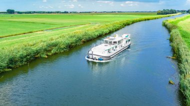 Hollanda 'nın kanal ve kırsal arazisindeki yüzen evlerin insansız hava aracı görüntüsü, mavna teknesi ve Hollanda' da tatille aile seyahati