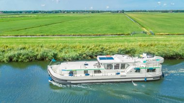 Hollanda 'nın kanal ve kırsal arazisindeki yüzen evlerin insansız hava aracı görüntüsü, mavna teknesi ve Hollanda' da tatille aile seyahati