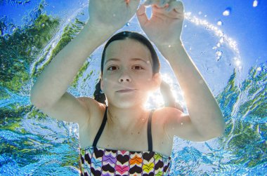 Çocuk yüzme havuzunda su altında yüzüyor, mutlu aktif genç kız dalıyor ve su altında eğleniyor, çocuk fitness ve tatil beldesinde aile tatilinde spor yapıyor.