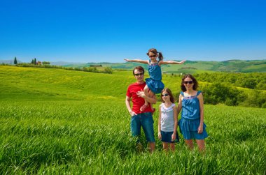 Çocuklu mutlu bir aile yeşil alanda eğleniyor. Baharda çocuklarla Tuscany, İtalya 'da tatil yapıyor.