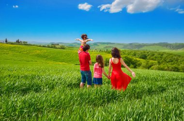 Çocuklu mutlu bir aile yeşil alanda eğleniyor. Baharda çocuklarla Tuscany, İtalya 'da tatil yapıyor.