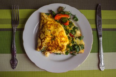 Doldurulmuş omlet, kahvaltı. Beyaz tabakta lezzetli bir yumurta tabağı var. Yukarıdan görüntüle.