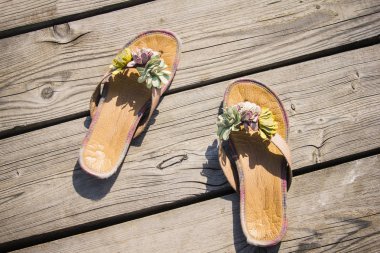 Female summer slippers on old wooden boards. Vacation, outdoor recreation, serenity. Bright sunlight. Top view, vignetting. clipart