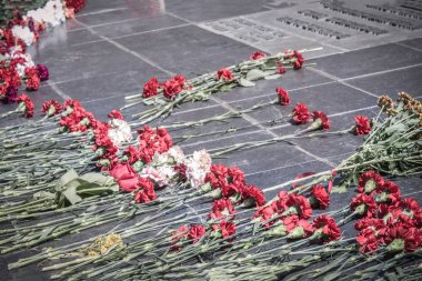 Granit bir levhada kırmızı karanfiller. Savaş kahramanlarının anısına, ölen askerlerin anısına. Kahramanlık, Anavatanın savunucularının kahramanca eylemi..