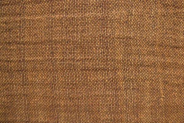 Natural material, organic fabric of home manufacture. Canvas texture, rough weaving. Warm yellow shades, homogeneous background.