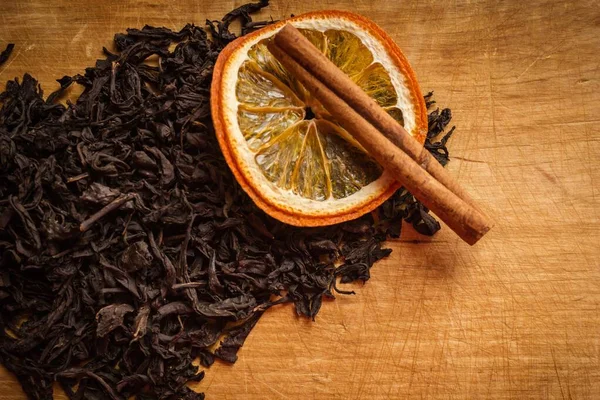 木製のキッチンテーブル 乾燥した紅茶 シナモンとオレンジの葉の上 暖かさ 快適さ 家庭料理 暖かいトーン ヴィネット — ストック写真