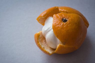 Tatlı bir mandalina görmeyi beklerken derinin altında acı sarımsak bulduk. Gösteriş, ikiyüzlülük, boş beklentiler, güzel bir ambalajın altında acı bir öz. Hafif arkaplan.