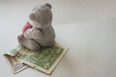 Hafif bir arka planda buruşmuş bir dolar ve yumuşak bir çocuk oyuncağı. Ucuz çocuk işçi kullanımı, düşük ödeme. Ses tonunu kapat. Bir seri üretim oyuncağı..