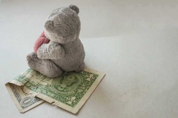 Hafif bir arka planda buruşmuş bir dolar ve yumuşak bir çocuk oyuncağı. Ucuz çocuk işçi kullanımı, düşük ödeme. Ses tonunu kapat. Bir seri üretim oyuncağı..