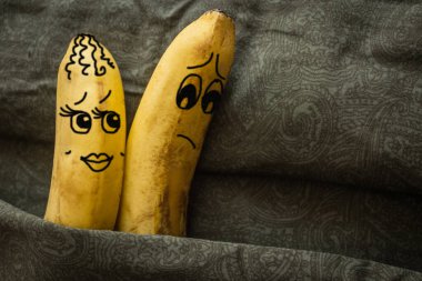 The wife inclines her husband to sex, he refuses. Two bananas in a family bed, dark background. Natural lighting, drawing made by the author. clipart