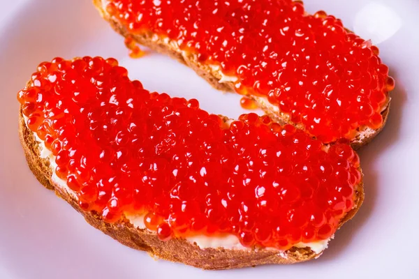 Bread is smeared with yellow oil, on top is a red, orange ket caviar. A natural source of protein, an expensive delicacy. Bon Appetit!