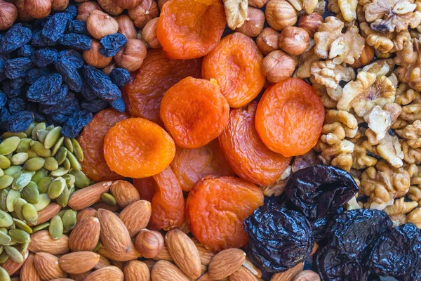 Useful food, proper nutrition. Abundance, assortment of nuts and dried fruits. In the center are orange apricots. Natural, organic product.