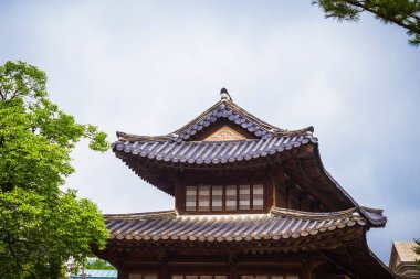 Güney Kore, geleneksel mimari. Yaz manzarası, yeşil ağaçlar, mavi gökyüzü. Eski bir ev, kıvırcık kiremitli çatı. Boşluğu kopyala.