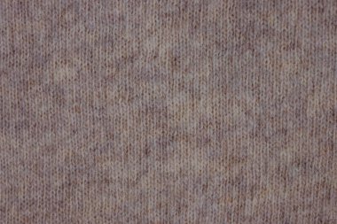 Doğal yünden örülmüş kumaş. Kalıpsız bej rengi. Küçük bir yığın, iplik teli. Doğal malzemelerden yapılmış ılık kışlık giysiler..