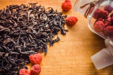 Kurutulmuş kırmızı böğürtlen, ahududu, siyah çaya güzel kokulu bir katkı. Geleneksel ev yemekleri, samimiyet, misafirperverlik. Doğal ahşap arka plan, eski mutfak tahtası..