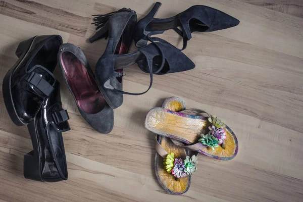 Dark, boring, working shoes aside, ahead frivolous sandals with flowers. Waiting for a holiday, a season of holidays, summer, rest, vacation. View from above.