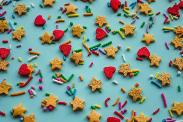 Red hearts and yellow stars on a light background. A fine colored dragee, fun, joy. Confectionery powder for cakes. Calm daylight.