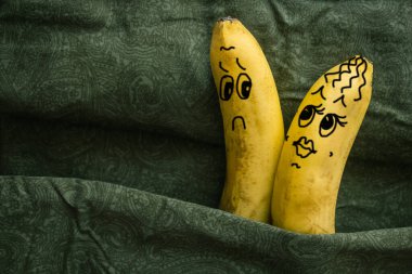 Passionate, sexy woman and a sluggish, cold man. Two bananas on dark sheets, a metaphor. Husband and wife, lovers. The picture is made by the author. clipart