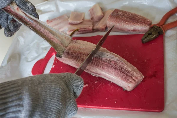Preparation of frozen fish for the national food of aborigines of the North, Far East, Siberia. Skin removal with a knife and pliers, chopping into pieces. Home kitchen.