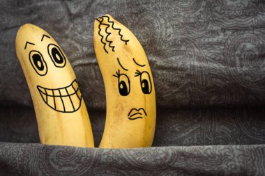 Family bed, dark sheets, two bananas nearby. The husband wants sex, the wife reluctantly yields. Coercion, domination. Daylight. The picture is made by the author. clipart