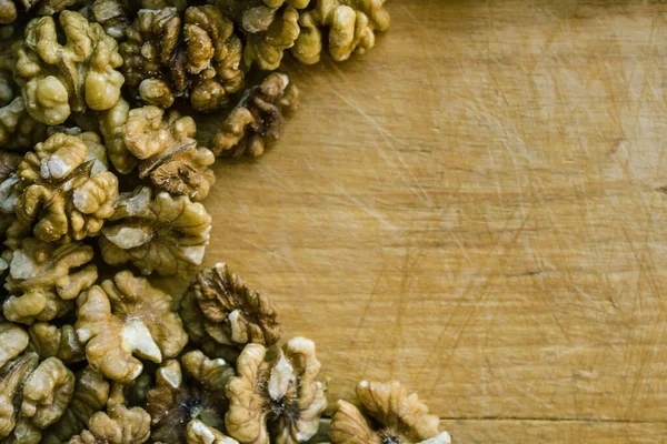 Natural, organic product, walnut kernels. Light wooden table with marks from the knife, scratches and cuts. Healthy lifestyle. View from above.