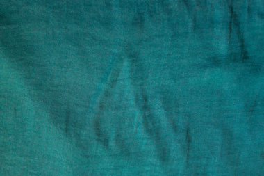 İnce ipek kumaşın dokusu koyu yeşil, zümrüt renginde. Eski bir şey, eski bir elbise. Gün ışığı.